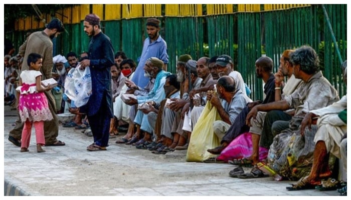 A representational image showing men distributing food to people. — AFP/File