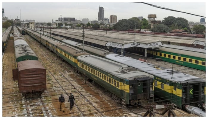 Policemen walk along trains stationed on a deserted platform at Karachi Cantonment railway station on March 26, 2020. — AFP