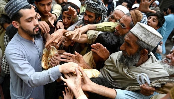 The representational image shows a person distributing meals among people.— AFP/File