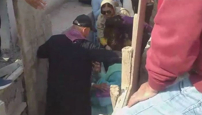 A screengrab taken from a video shows people trying to pull out Noreen Niazi from under-construction sewerage line. — Geo News