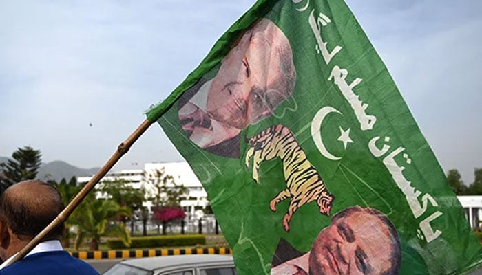 A supporter of PML-N holds a party flag with images of Shehbaz Sharif and his elder brother and three-time prime minister Nawaz Sharif. — AFP/File