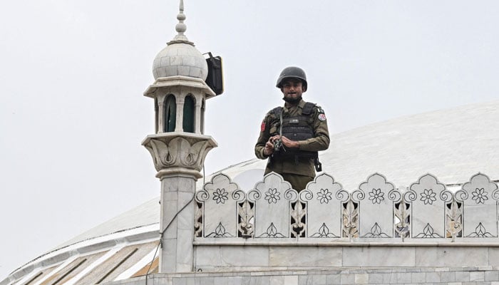 A security personnel stand guard as Muslim devotees offer Friday prayers during the Islamic holy fasting month of Ramadan at a mosque in Lahore on February 27, 2026. — AFP