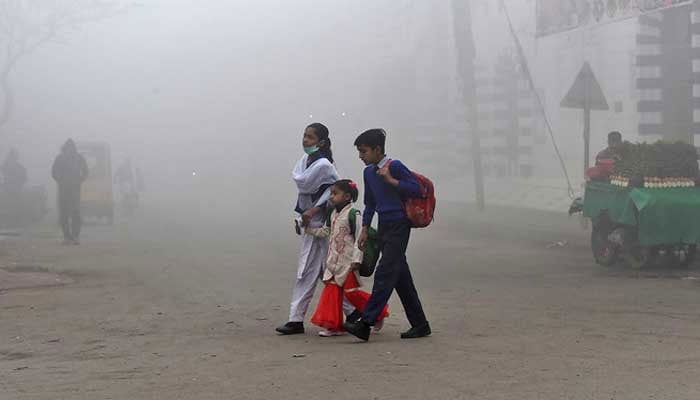 Children cross a street on their way to school amid heavy smog conditions in Lahore, Pakistan, on February 12, 2021. — AFP