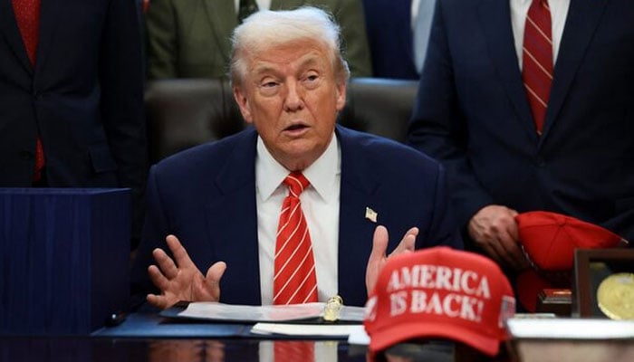 US President Donald Trump sits at his desk, behind a hat that reads America is back at the White House in Washington, DC, US, February 3, 2026. —Reuters