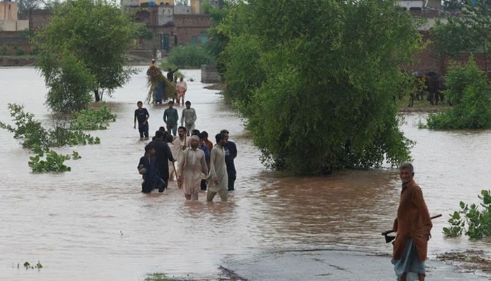 Residents wade through a flooded road, following the monsoon rains and rising water level of the Chenab River, in Patraki, Chiniot district of Punjab, August 30, 2025. — Reuters