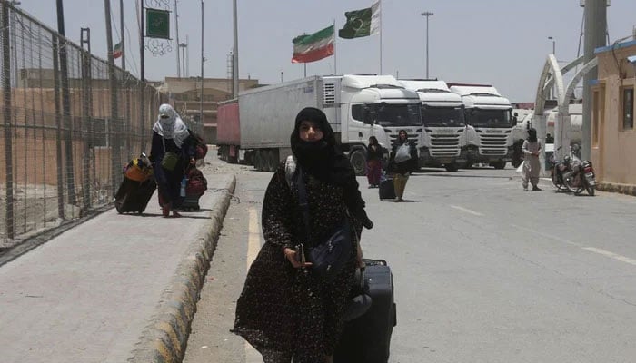 This representational image shows a Pakistani pilgrim along with others walks with her belongings after she returned from Iran on June 19, 2025. — Reuters