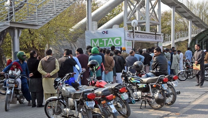 People stand in a queue to install E-tags/M-tags for their motorcycles along the Islamabad Expressway, in the Federal Capital on February 22, 2026. — Online