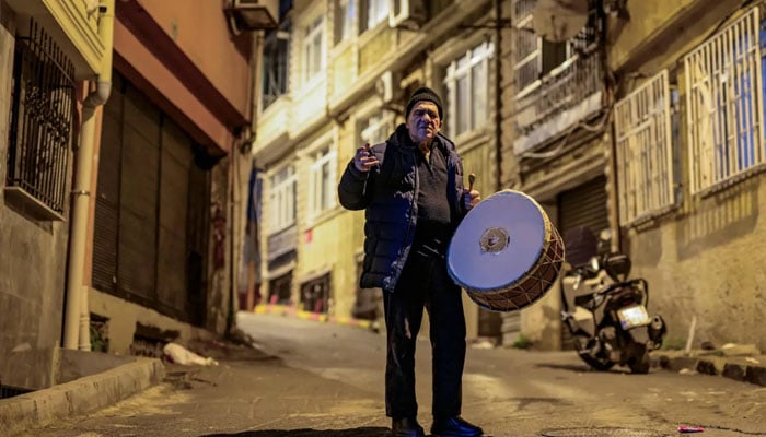 Turkish drummer Hakan Ozbingol plays drum and sings traditional songs in the streets of Istanbul, to wake Muslims up for the suhour, the Ramadan meal eaten at night, on February 24, 2026. —AFP
