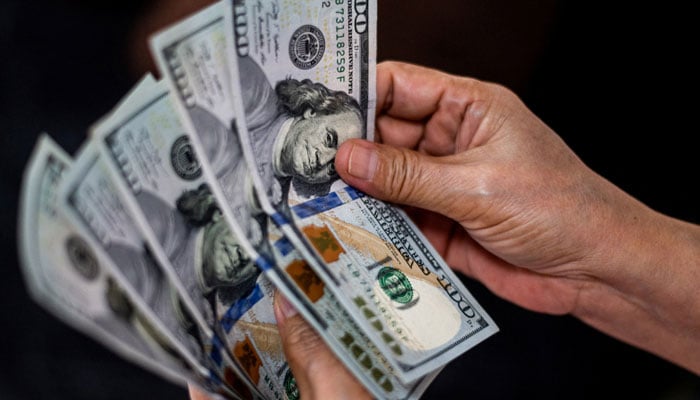 A person shows US dollars at a currency exchange store. — Reuters/File