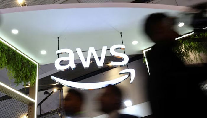 People walk past the logo of Amazon Web Services (AWS) at its exhibitor stall at the India Mobile Congress 2025 at Yashobhoomi, a convention and expo center in New Delhi, India, October 8, 2025.—Reuters
