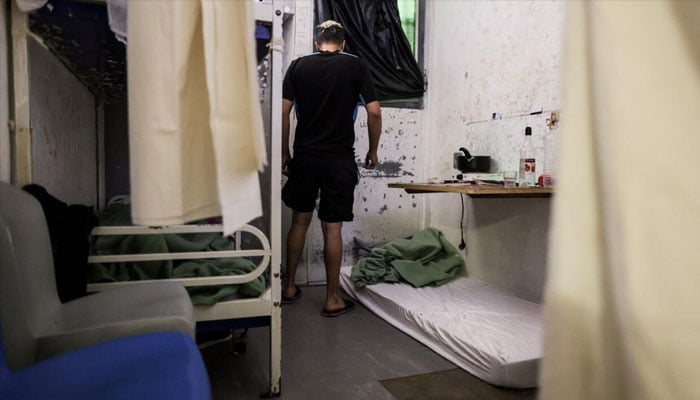 An inmate stands in his two-person cell near a mattress set for a third inmate at Gradignan prison, near Bordeaux, southwestern France, on October 3, 2022.—AFP
