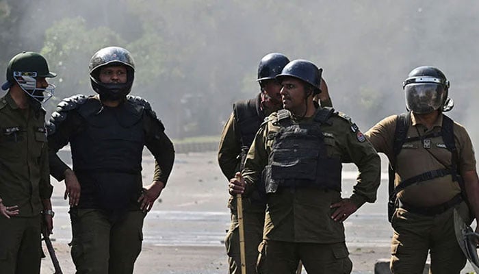 Policemen stand guard as Pakistan Tehreek-e-Insaf party activists and supporters protest against the arrest of Imran Khan in Lahore on May 11, 2023. — AFP