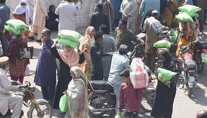 The representational image shows people standing in a queue to collect free wheat flour bags from Ramadan Package in Lahore, on March 28, 2023. — Online