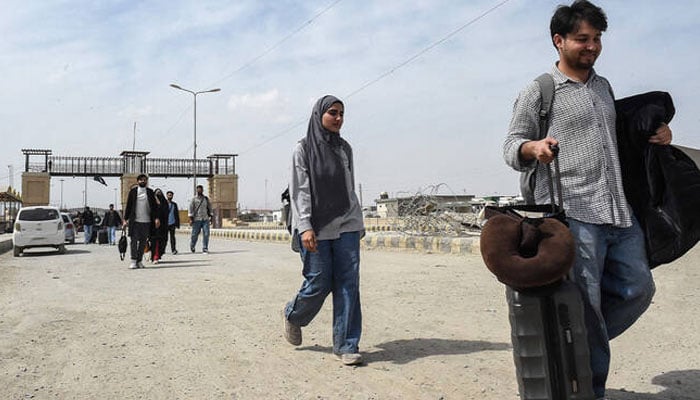 Pakistani nationals walk across a border after returning from Iran, in Balochistan province, Pakistan, on March 2, 2026. — AFP