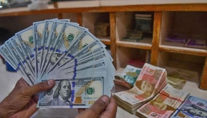 A foreign currency dealer counts US dollars at a shop in Karachi, Pakistan, on May 19, 2022. — AFP/File