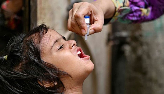 A health worker administers polio drops to a child for vaccination on the first day of a nationwide week-long poliovirus eradication campaign in Karachi on May 26, 2025. — AFP