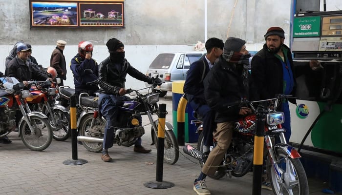 People wait for their turn to get fuel at a petrol station in Peshawar, on January 24, 2023. — Reuters