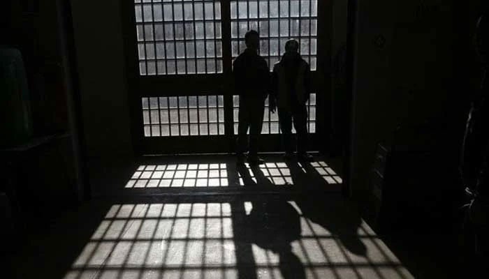 A silhouette of two prisoners standing inside a jail. — Reuters/File
