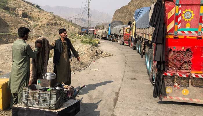 A tea vendor stands near the stalled vehicles near the closed Pakistan-Afghanistan border town of Torkham on October 19, 2025, after cross-border clashes between the two countries. — AFP
