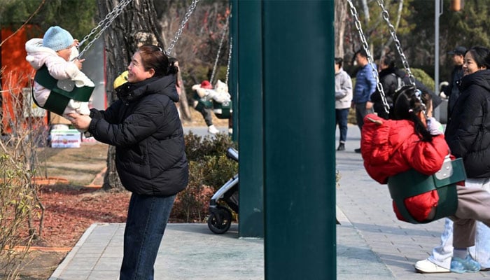A Chinese mother entertaining her child on a swing. —AFP/File