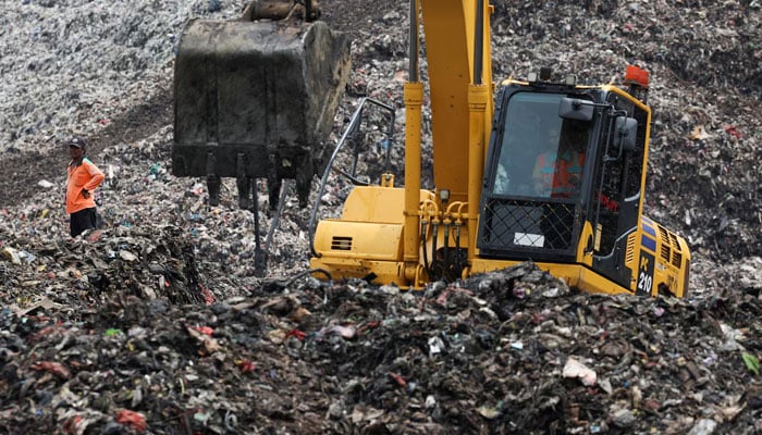 A worker stands amid garbage at the site of a collapse at the Bantar Gebang landfill, while an excavator operates during a rescue operation in Bekasi, on the outskirts of Jakarta, Indonesia, March 9, 2026. — Reuters