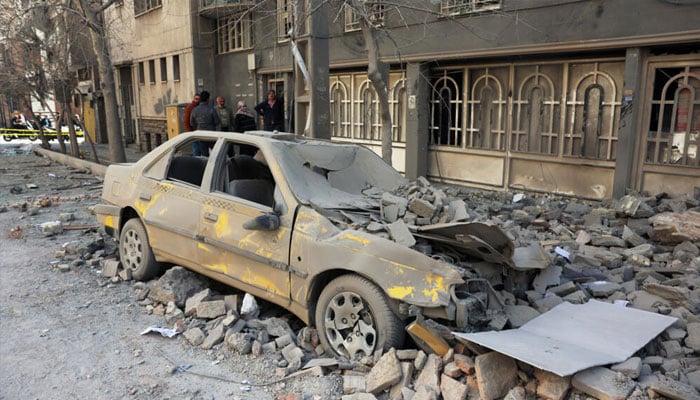 Residents stand amid the debris of a building following air strikes in central Tehran. —AFP/File