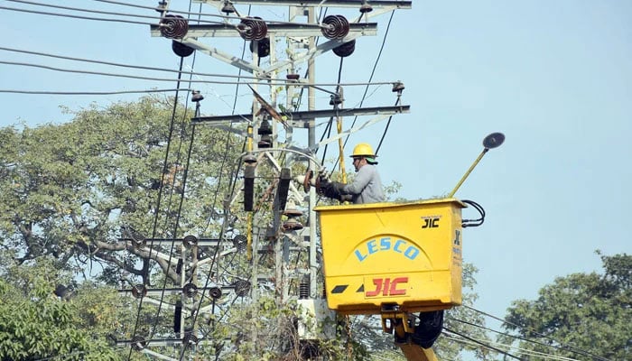The representational image shows a Lesco worker repairing high voltage electric wires on a pole alongside a road, in Lahore on December 9, 2024. — Online
