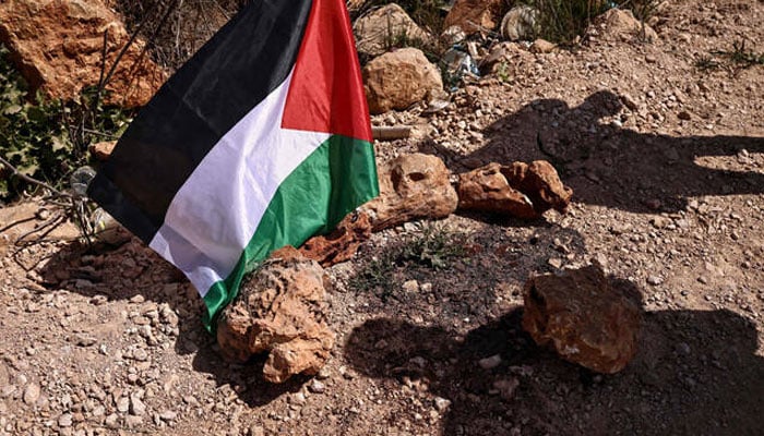 A Palestinian flag is placed at the site where a Jewish settlers attack killed 3 Palestinians and injured 7 others in the village of Abu Falah, on March 12, 2026.—AFP