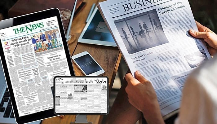 A person reads a newspaper, whereas the tablets show The News e-paper editions open on the screen. — Jang Media Group/File