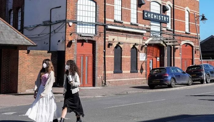 Pedestrians (left) wearing face masks walk past Club Chemistry (right), a nightclub linked to a recent outbreak of meningitis in Canterbury, south-east England on March 18, 2026. — AFP