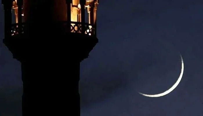A new crescent seen through a telescope shines beside the tower of a mosque. — Reuters/File