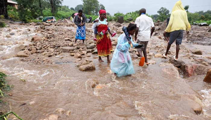 Locals in the Chiradzulu district walk through a flooded road after mudslides and rockfalls in the area caused by the aftermath of Cyclone Freddy in Blantyre, Malawi, March 15, 2023. — Reuters