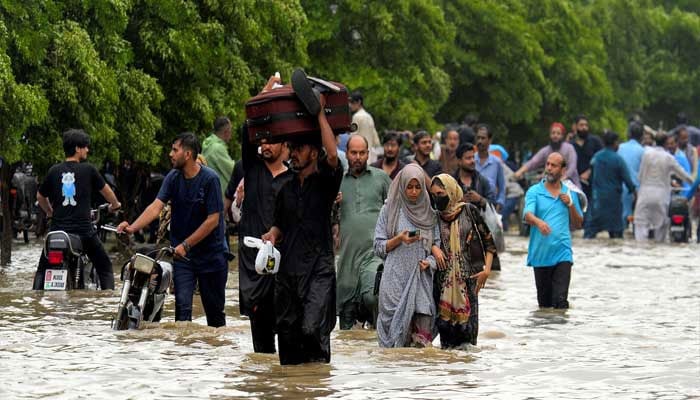 People wade through a flooded road after the monsoon rain in Karachi, Pakistan, August 19, 2025. — Reuters