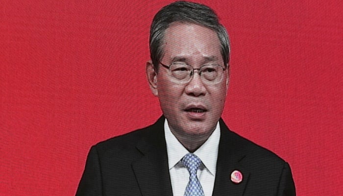 Chinese Premier Li Qiang seen on a big screen live broadcasting his speech at the opening of the China Development Forum. —AFP