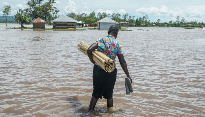 A woman in Kenyas Nyakach region wades through flooding triggered by torrential rain. —AFP/File