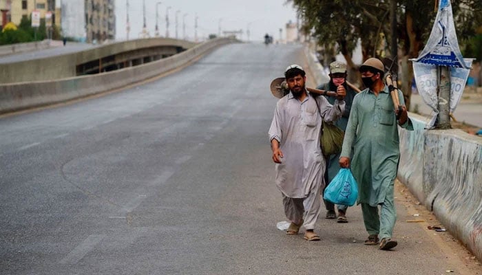Labourers walk on a deserted street during a lockdown in Karachi, March 24, 2020. — AFP