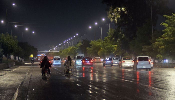 Commuters on their way at Faizabad bridge during rain, in the Federal Capital on March 25, 2026. — Online