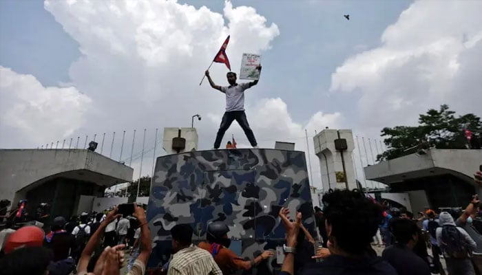 A demonstrator waves a flag as he stands atop a vehicle near the entrance of the Parliament during a protest against corruption and government’s decision to block several social media platforms, in Kathmandu, Nepal September 8, 2025. — Reuters