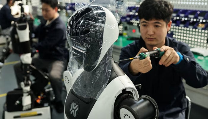 Employees assemble robots at the production line during organized media tour to the Robotics Pilot Testing and Validation Platform of Beijing Innovation Center of Humanoid Robotics (X-Humanoid) in Beijing, China, March 20, 2026. — Reuters