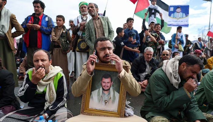 A Houthi supporter holds a poster with an image of the Houthis’s leader, Abdul-Malik al-Houthi, as he speaks on a mobile phone during a demonstration in solidarity with Iran, as the US-Israeli conflict with Iran continues, in Sanaa, Yemen, March 27, 2026.—Reuters