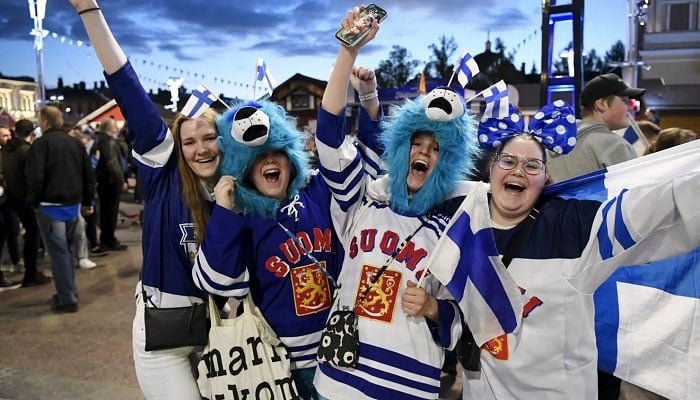 Finnish youth share a laugh while dressed in Finland‑coloured attire at an event. — AFP/File