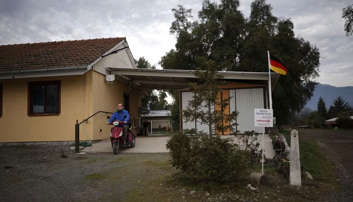 Rudiger Schmidtke leaves his house riding his electric tricycle in Villa Baviera, formerly Colonia Dignidad, on the outskirts of Parral, Chile. —Reuters