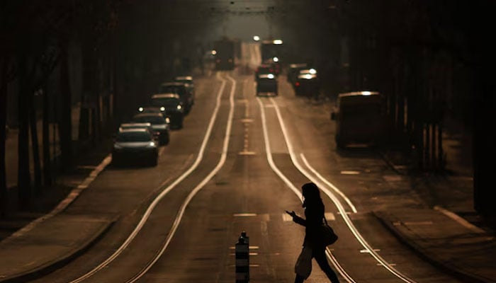 A woman crosses a street while using a mobile phone in Bern, March 4, 2011.—Reuters