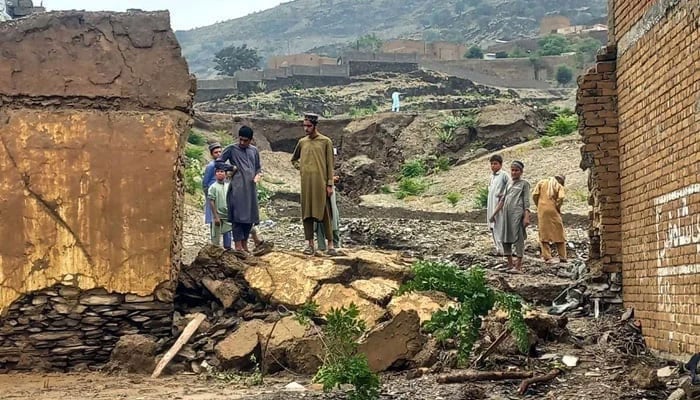 People stand near a collapsed wall after floods due to heavy monsoon rain in Khyber Pakhtunkhwa. — PPI/File