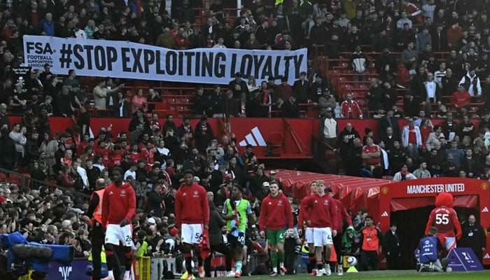 Manchester United fans, many wearing black as a protest, display a banner in the crowd against seat prices and the current ownership of Manchester United ahead of the English Premier League football match between Manchester United and Arsenal at Old Trafford in Manchester, northwest England, on March 9, 2025. —AFP