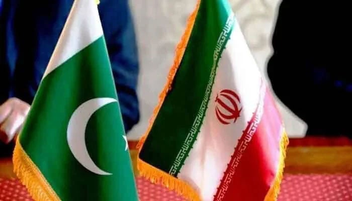 The image features the national flags of Pakistan (left) and Iran (right) displayed on small poles, typically seen during diplomatic meetings or events. — The News/File