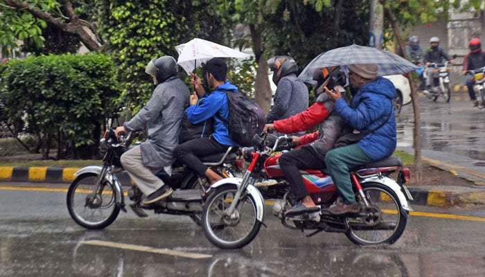 Motorcyclists covered themselves with a plastic sheet while riding motorcycle on their way at a road during rain, in the Provincial Capital on March 19, 2026. — Online