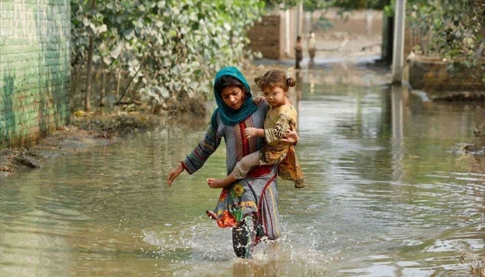 The representational image shows a girl carrying her sibling as she walks through stranded flood water, following rains and floods during the monsoon season in Nowshera, Pakistan September 4, 2022. — Reuters