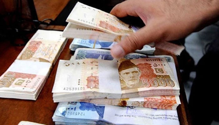 A person arranges stacks of Pakistani banknotes. — AFP/File