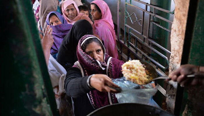 Residents receive donated food at a distribution point at the Bari Imam shrine in Islamabad, February 9, 2017. — AFP